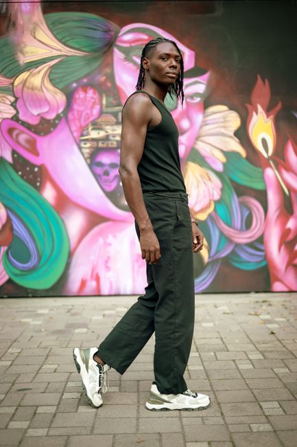 Stylish man in streetwear walking by a colorful graffiti wall.