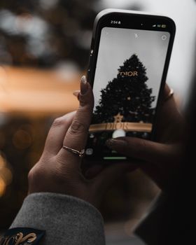 A woman photographs a Dior Christmas tree with her smartphone in Toronto.