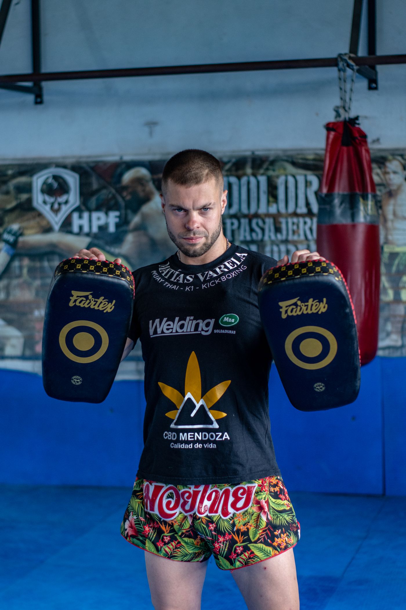 Adult kickboxer training with kick pads in a gym.