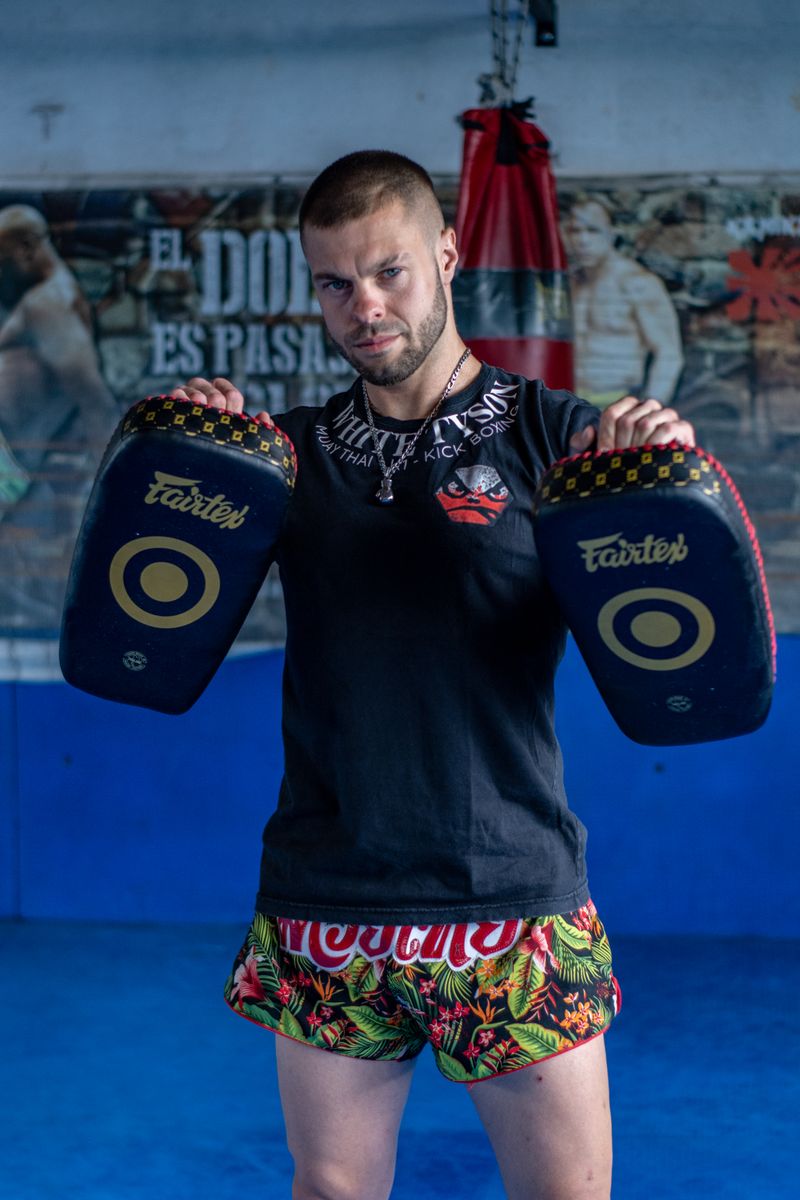 Muay Thai trainer holding focus pads ready for training