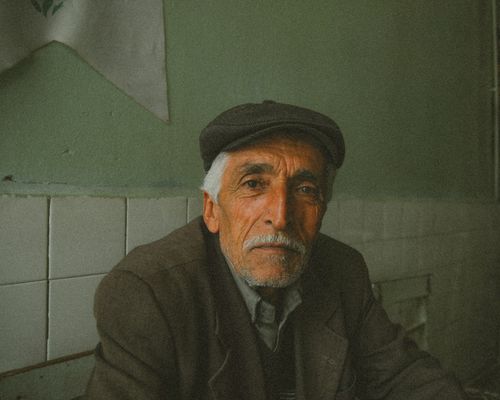 Free Portrait of an elderly man wearing a flat cap and suit, reflecting wisdom and experience. Stock Photo