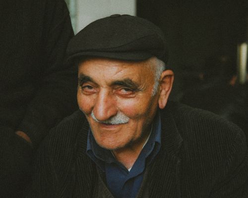 Free Warm and inviting portrait of an elderly man wearing a flat cap, smiling gently. Stock Photo
