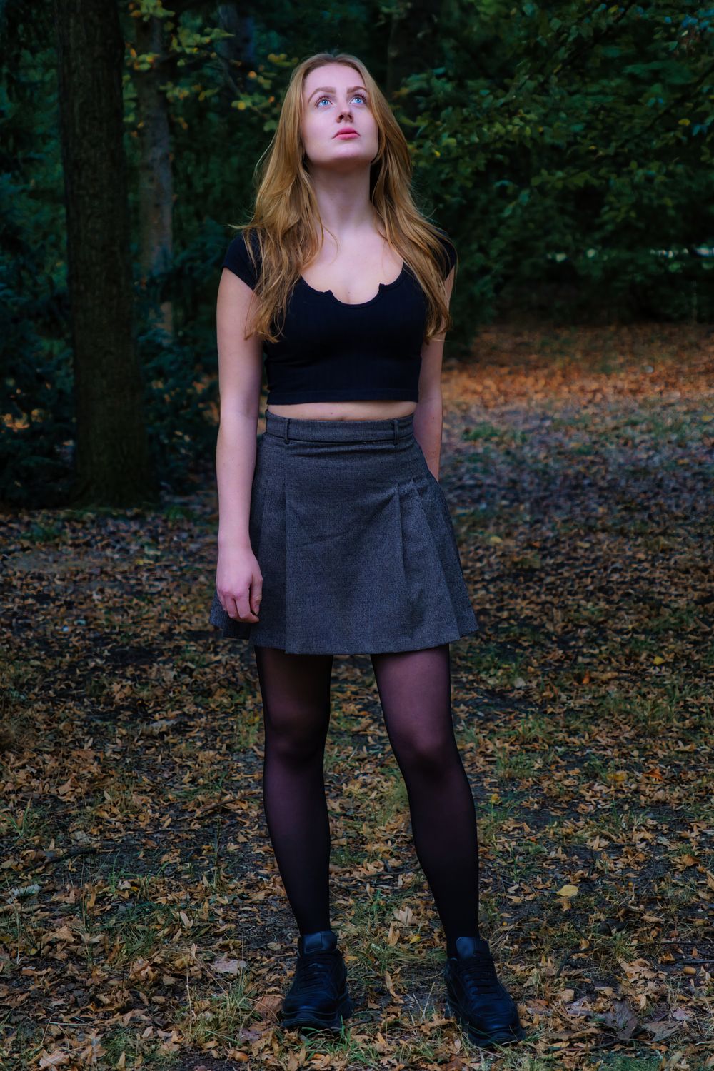 Young Woman in a Skirt Standing in a Park and Looking Up · Free Stock Photo