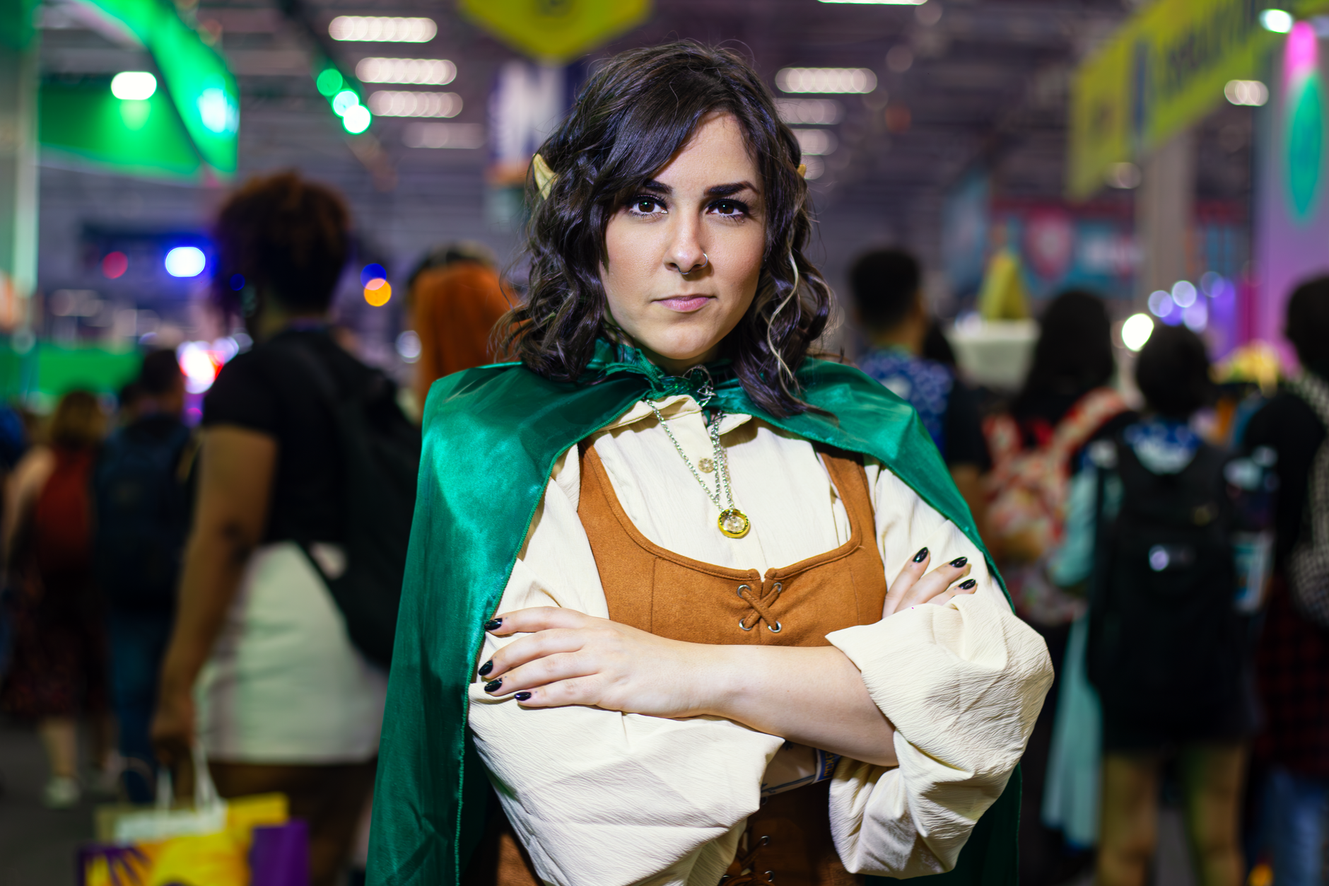 A young woman in cosplay attire posing confidently at a bustling fan event.