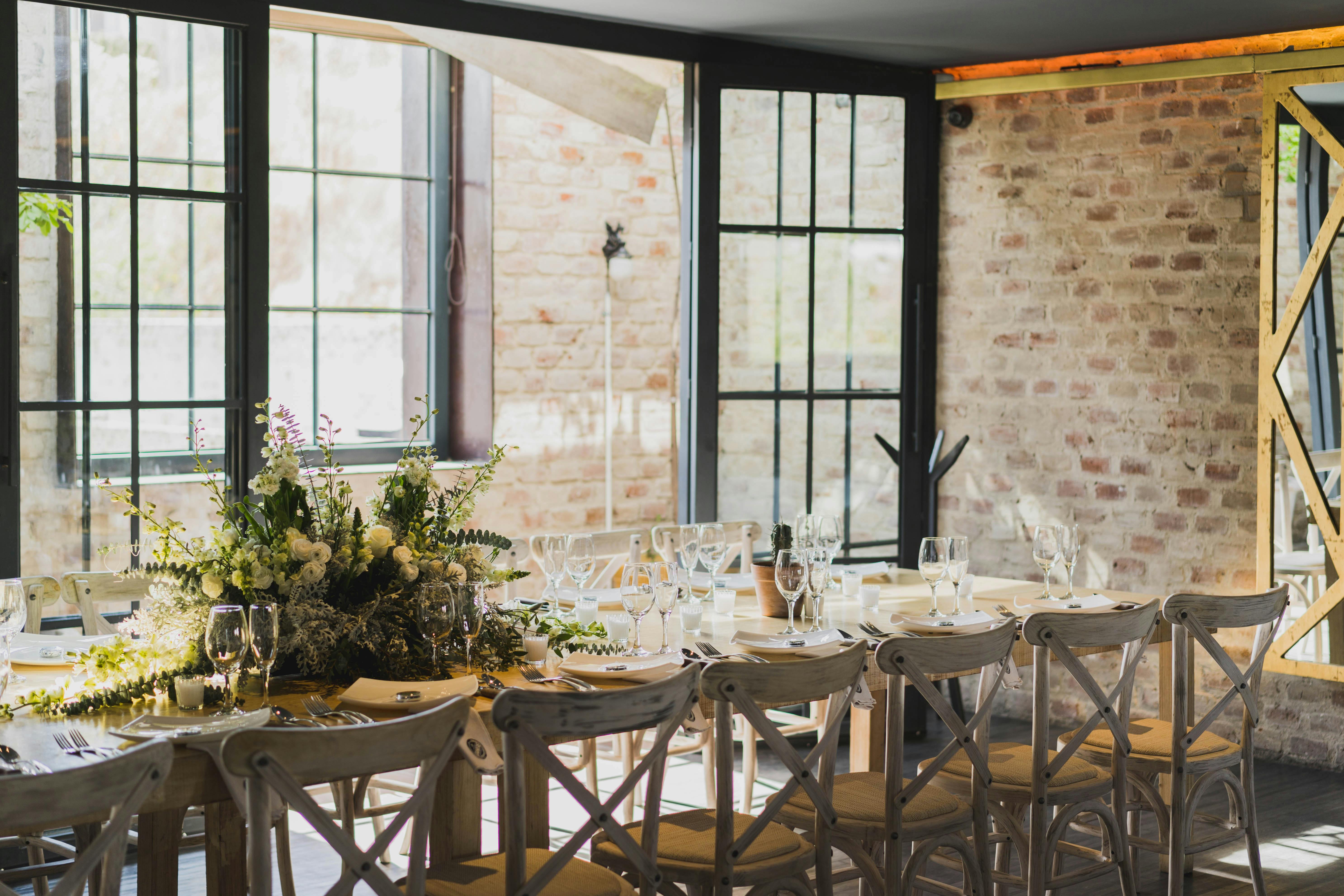 Elegant table setting in a León restaurant, with floral centerpiece and natural light.
