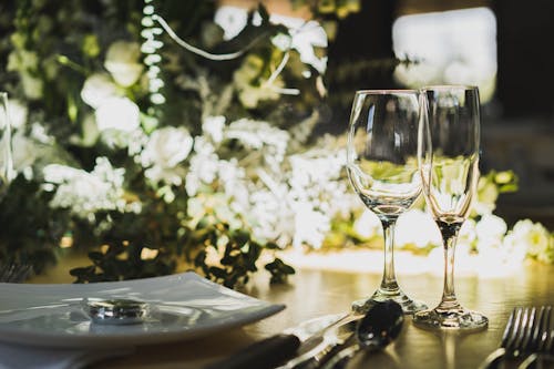 Close-up of Dinnerware and Glassware next to a Flower Arrangement on a Table 