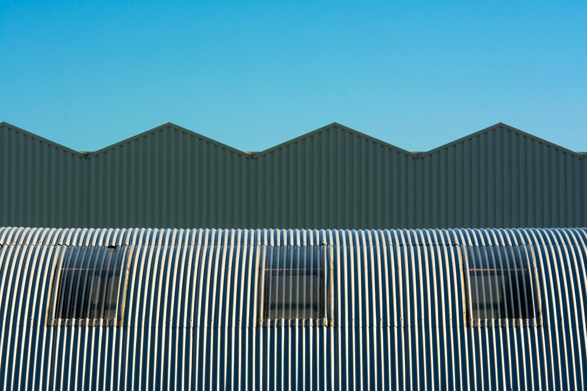 Industrial warehouse with corrugated and cylindrical roof design showcasing geometric structure.