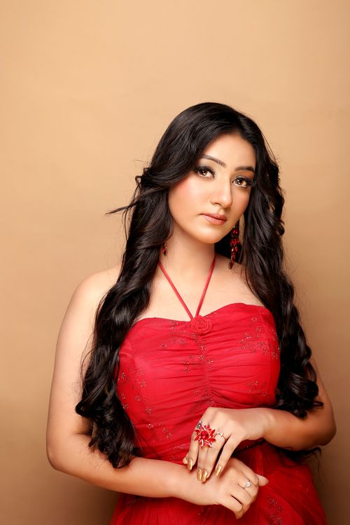 Free Stunning portrait of a brunette woman in a glamorous red dress set against a neutral background. Stock Photo
