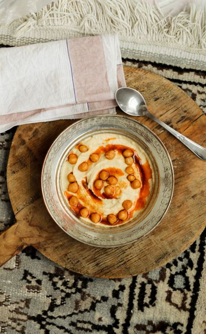 Aerial view of chickpea hummus with paprika on a vintage plate with spoon and napkins.