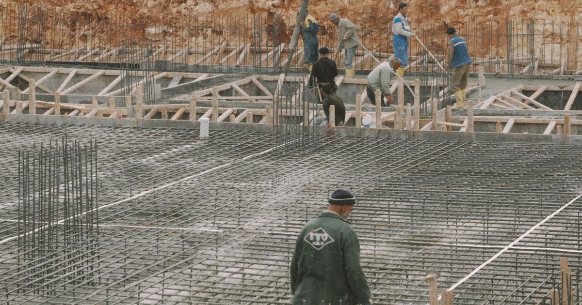 建設現場で作業員が格子状に組んだ鉄筋の上で作業している
