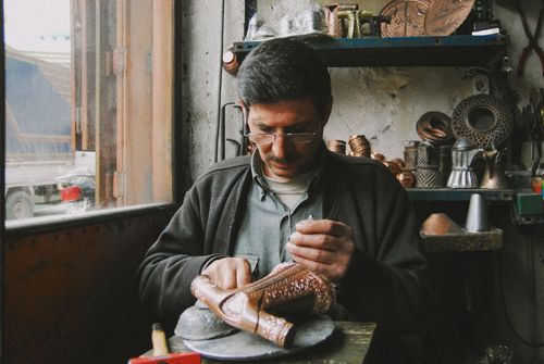 Free A skilled artisan engraving a detailed brass figurine in a workshop setting, demonstrating craftsmanship. Stock Photo