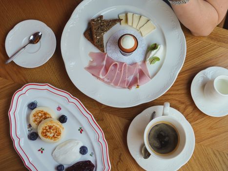 A sophisticated breakfast spread featuring coffee, ham, eggs, and cheese on a wooden table.