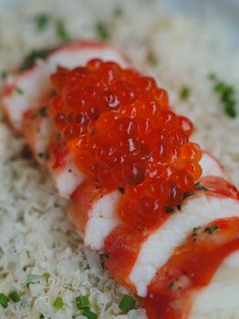 Delicious sushi roll topped with vibrant red caviar, showcasing luxury and freshness.