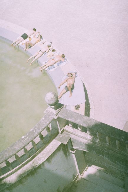 People sunbathing by a pool in Lisbon, capturing a serene summer moment.