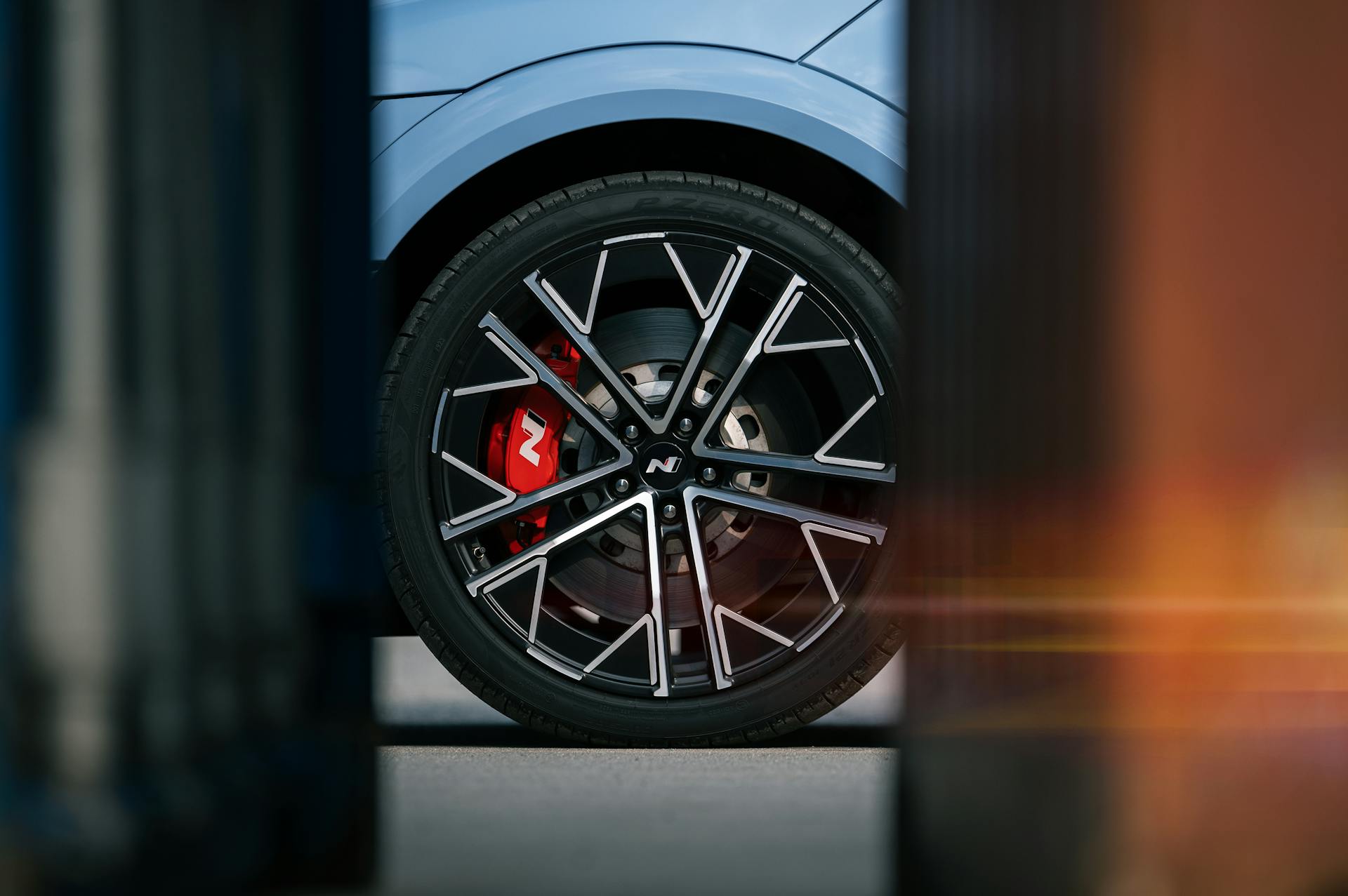 Close-up view of a modern car wheel with sharp design and red brake caliper, showcasing sleek automotive style.