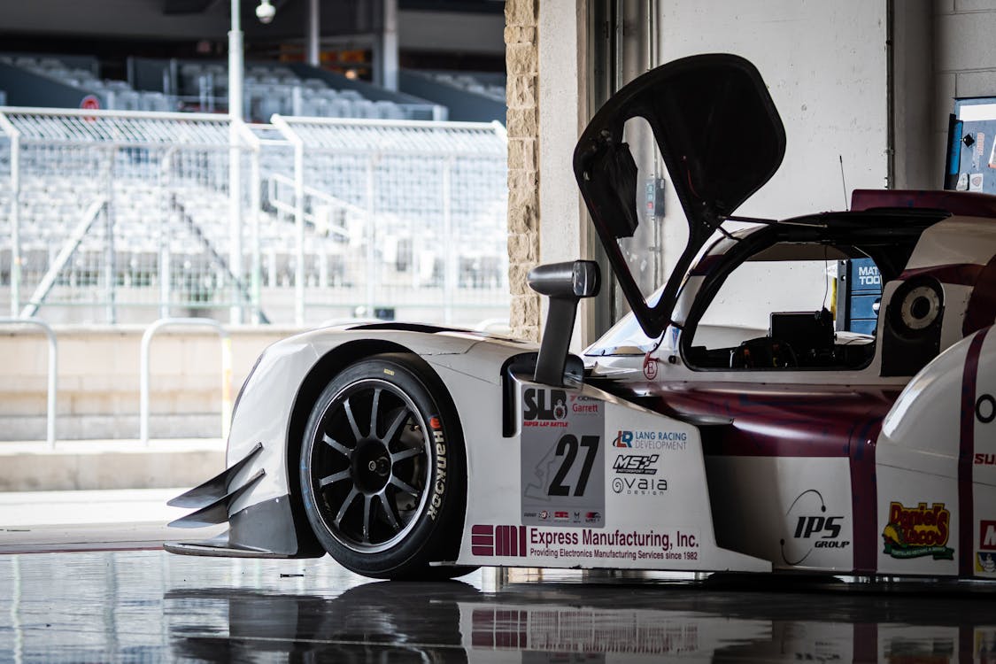 A Race Car Parked in a Garage with View of the Grandstands by a Race Track 