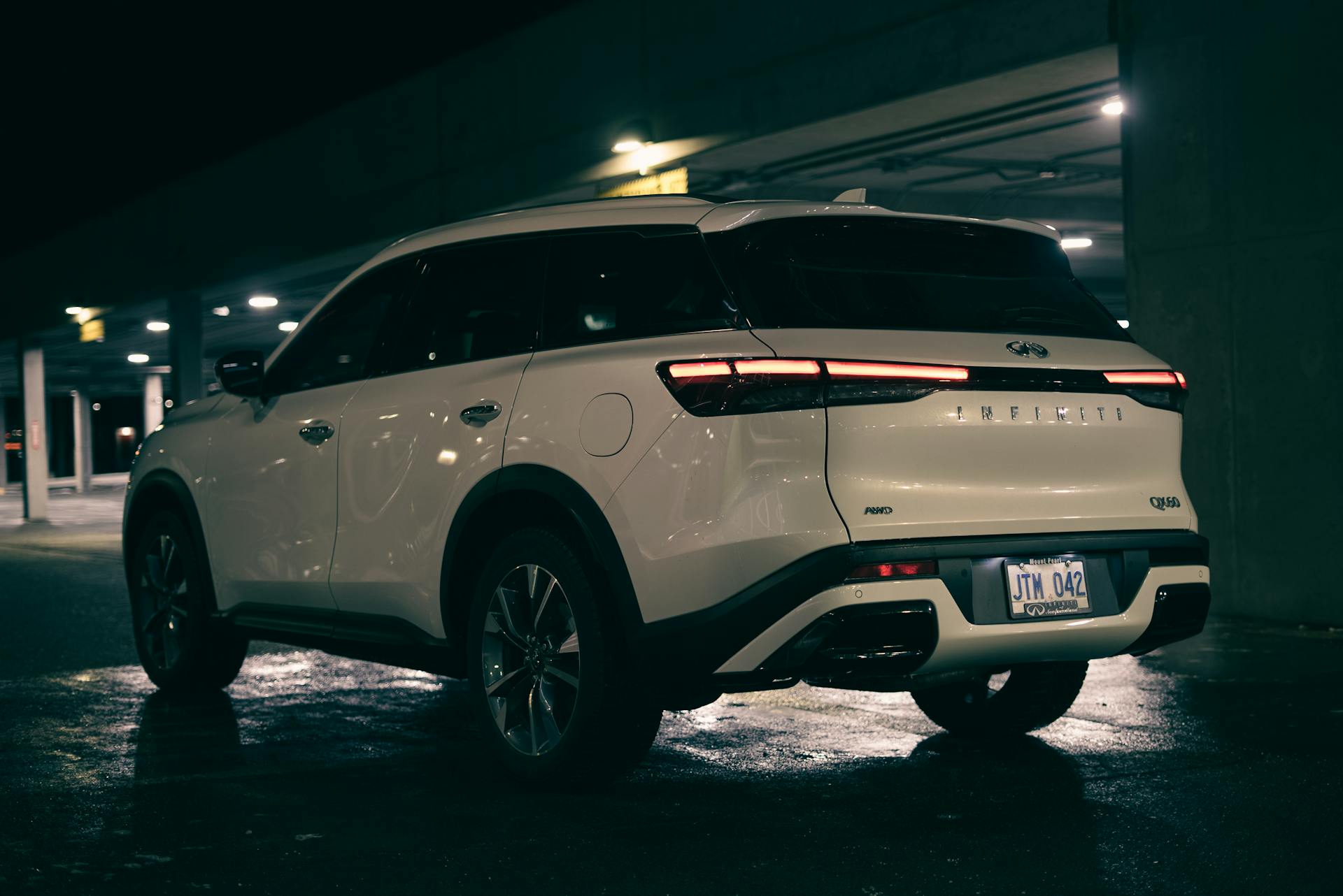 A sleek Infiniti SUV parked at night, highlighting its modern design in an urban garage setting.