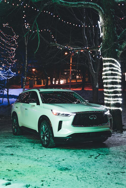 White Infiniti QX60 Luxury Crossover Parked Under a Tree Decorated with Christmas Lights