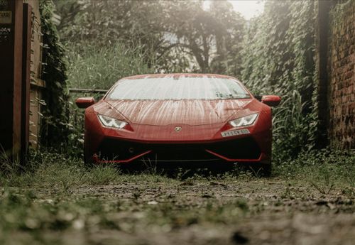 Free A striking red sports car parked in a lush, rainy outdoor setting in Sant'Agata Bolognese, Italy. Stock Photo