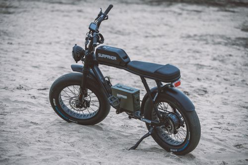Free A black electric bicycle with surpanda branding on sandy outdoor terrain, showcasing modern design and features. Stock Photo