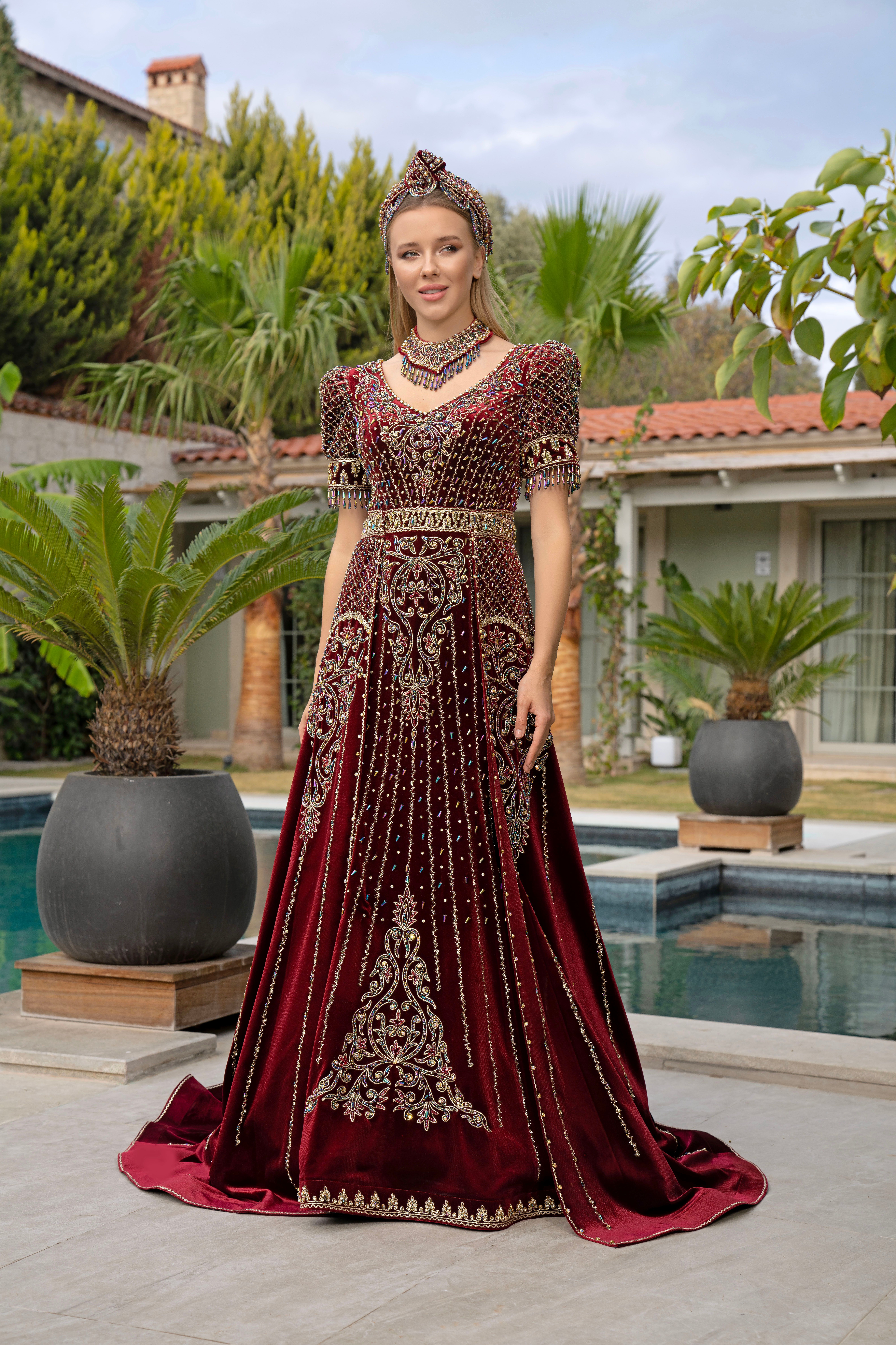 Stunning Ottoman-style gown with intricate embroidery, perfect for an outdoor bridal or ceremonial event.