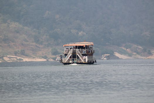 Passenger ship sailing through a tranquil rural river setting, offering scenic views.