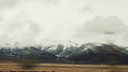 Free Beautiful snowy mountain range with clouds hovering above, creating a dramatic winter landscape. Stock Photo