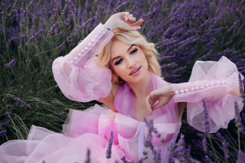Free Blonde woman in a flowing pink dress posing confidently amidst vibrant lavender blooms. Stock Photo
