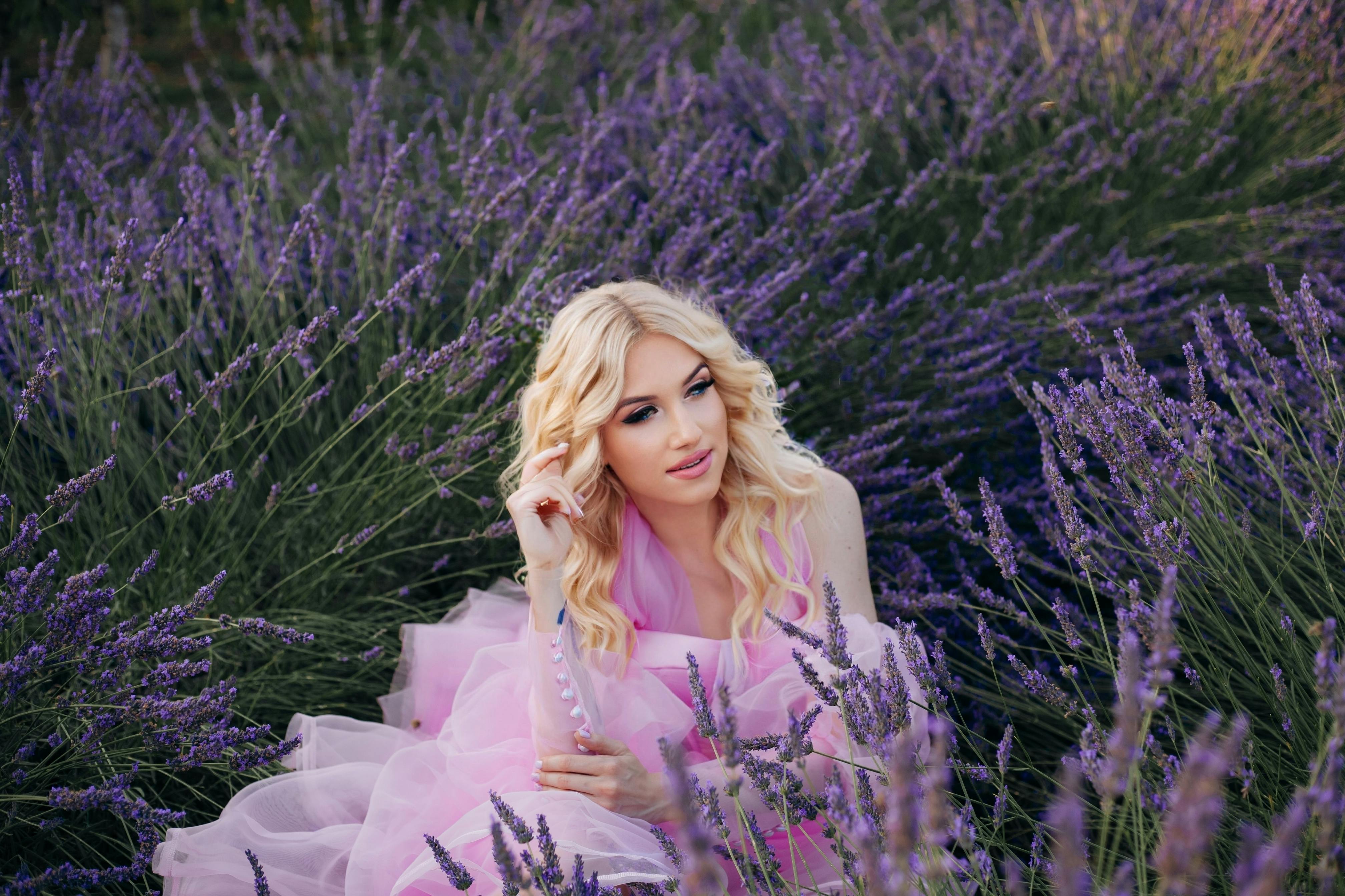 A blonde woman in a pink dress poses in a beautiful lavender field in Cyprus, epitomizing summer elegance. - Photo by Karina Rymarchuk on Pexels