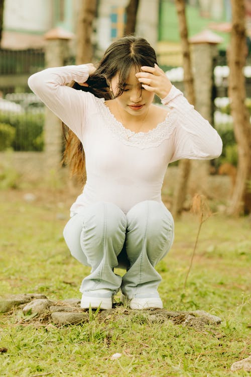 Young Woman Crouching on the Stones in the Yard