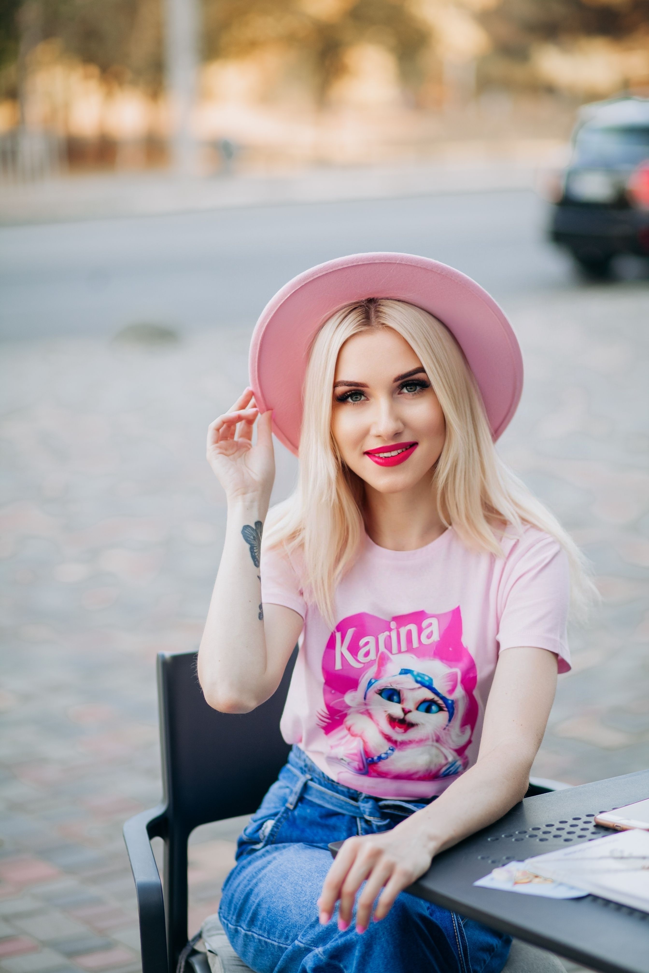 Smiling young woman in a pink hat and t-shirt enjoys a sunny day outdoors. Lifestyle portrait.