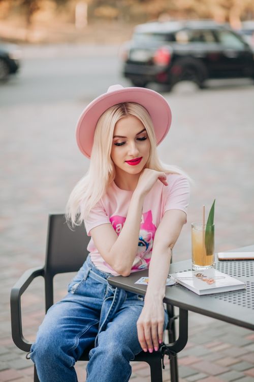 Free Fashionable woman in pink hat enjoying a summer day at an outdoor café in Valencia, Spain. Stock Photo