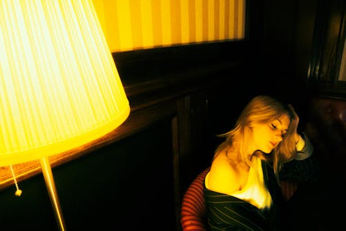 Blonde Woman Sitting near Lamp
