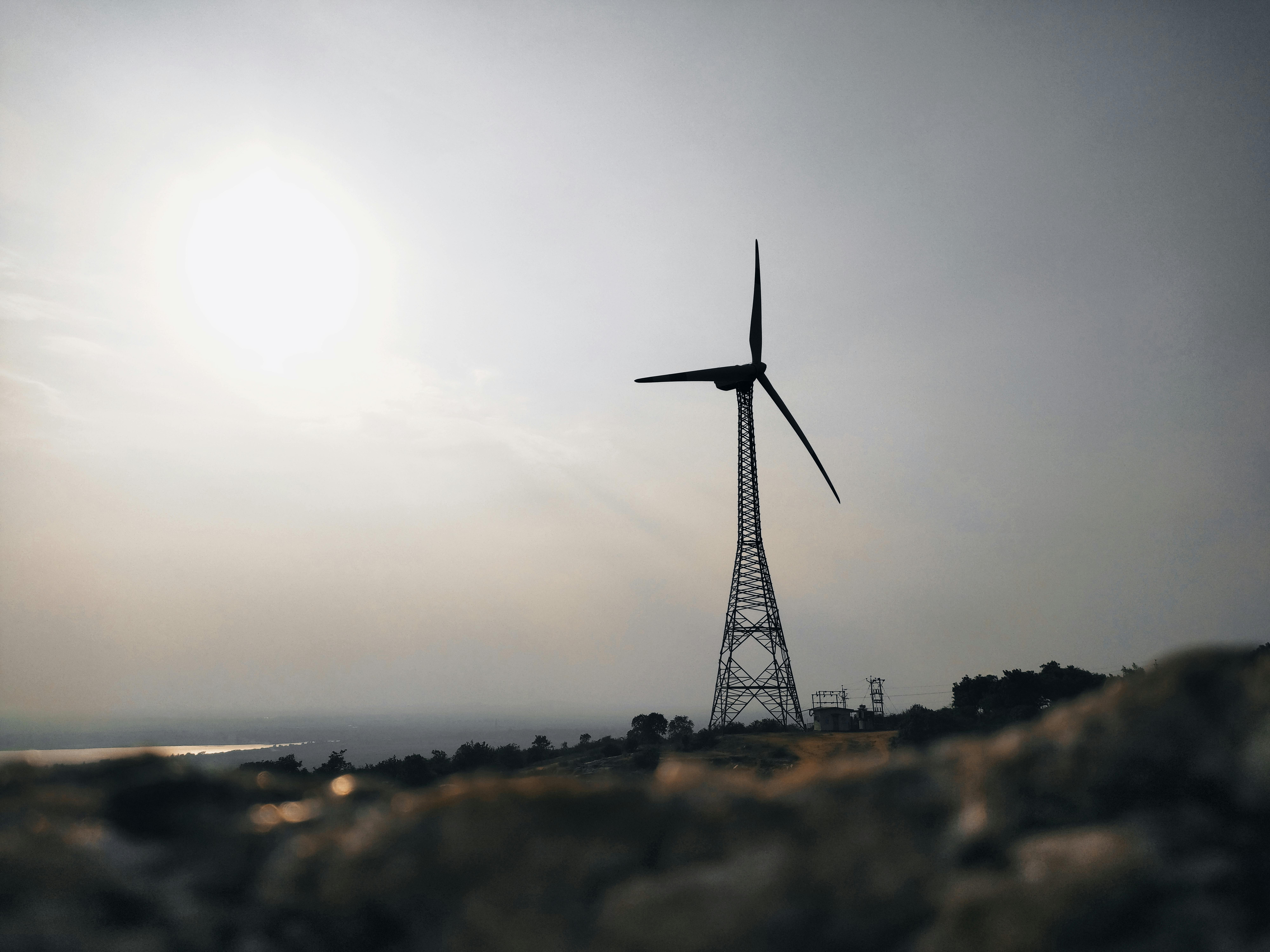 A wind turbine stands tall against a serene, sunlit landscape, promoting renewable energy.