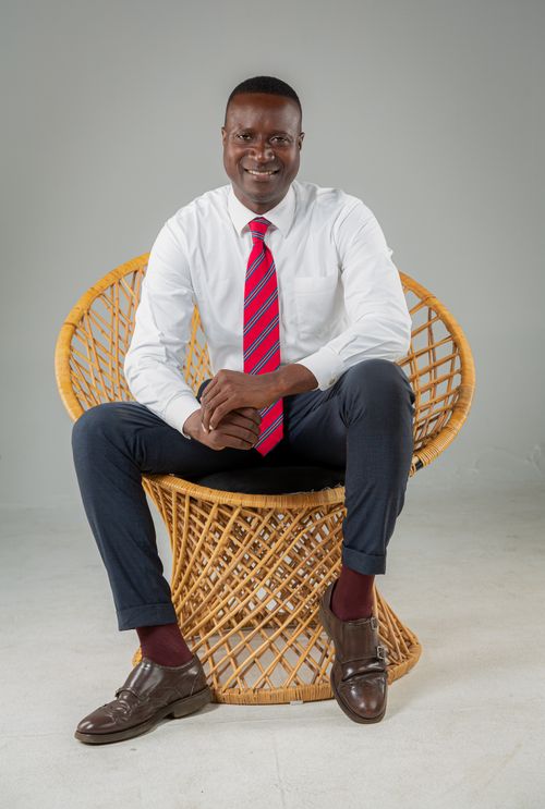 Free Stylish young man in white shirt and red tie sitting on rattan chair in studio. Stock Photo