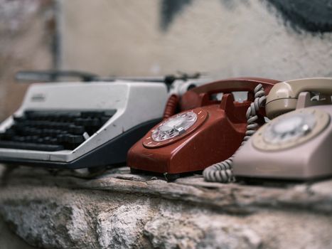 Rustic display of an old typewriter and rotary phones, embodying nostalgia.