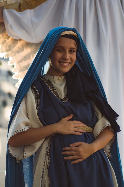 Free Woman dressed as the Virgin Mary in a Christmas pageant, smiling warmly. Stock Photo