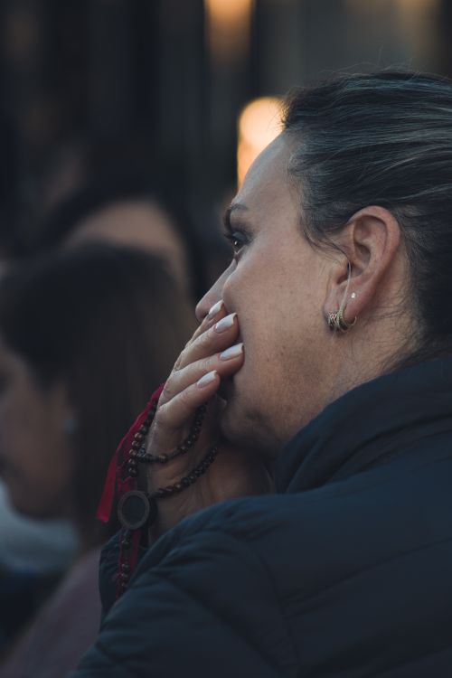 Free A woman in deep thought, holding beads to her face, captured in a close-up side profile. Stock Photo