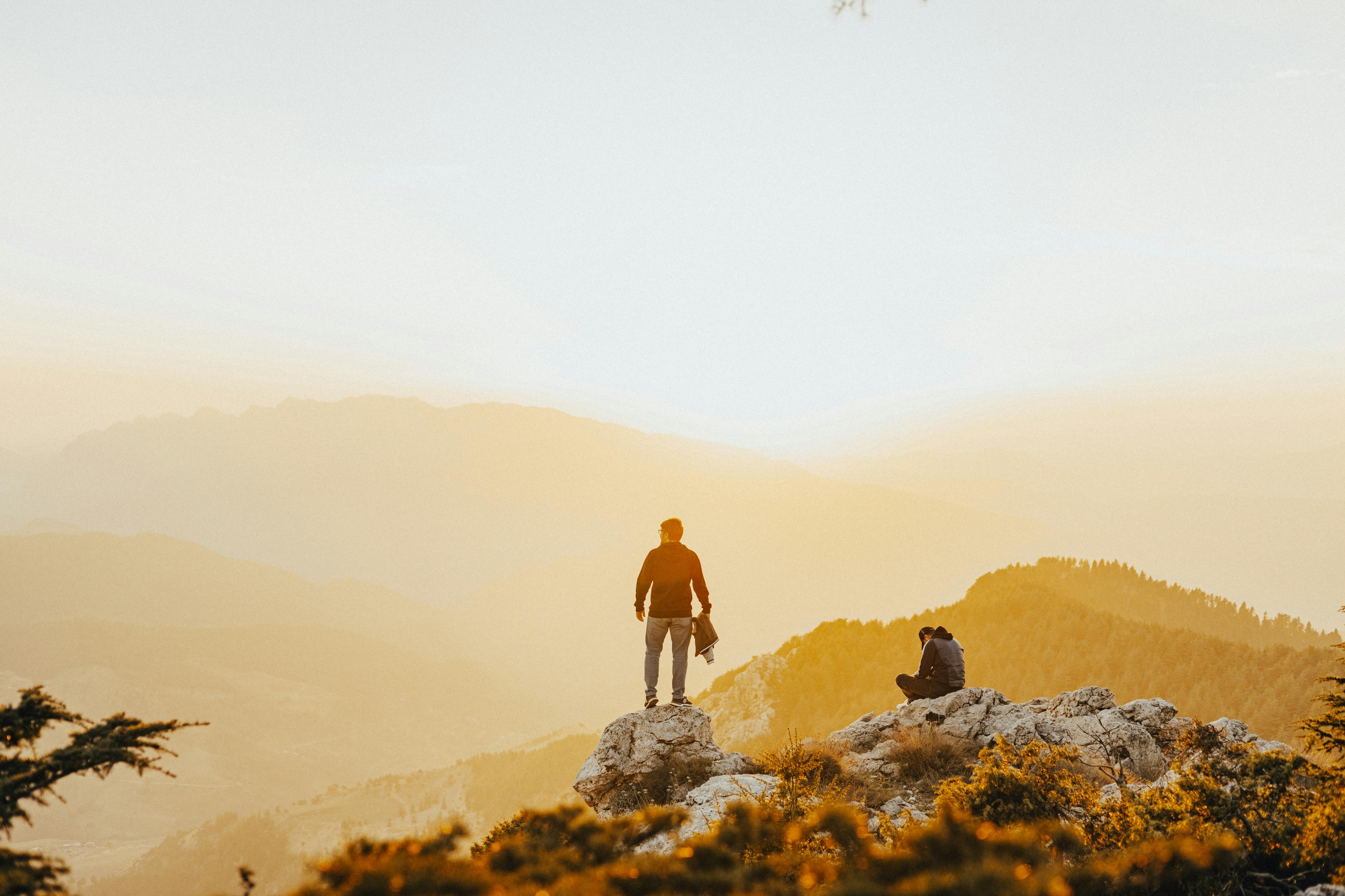 Two hikers enjoying a stunning mountain view at sunset. Perfect for adventure and nature enthusiasts.
