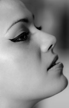 A striking black and white profile portrait of a woman with dramatic makeup.