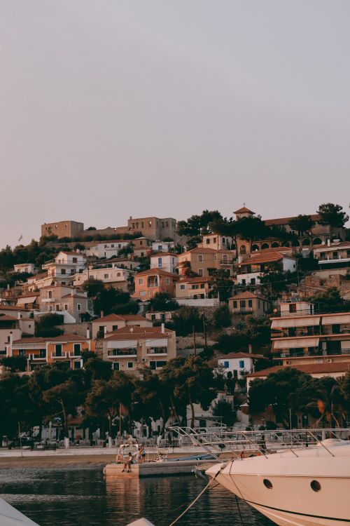 Free Captivating view of sunlit houses on a hill in Paralio Astros, Greece, overlooking a serene harbor. Stock Photo