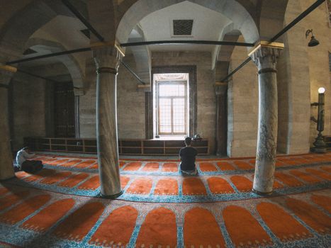 A serene moment of prayer inside a beautifully lit mosque with traditional architecture.