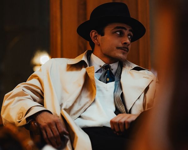 Man in hat and coat sitting outdoors