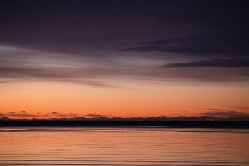 Free A beautiful sunset reflecting on tranquil ocean waters with a dramatic sky. Stock Photo