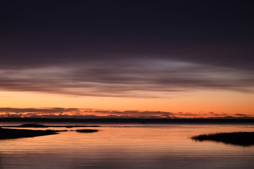 Free A tranquil sunset scene with dramatic skies over a calm body of water reflecting the colors. Stock Photo