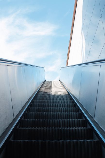 Looking up an escalator towards a vibrant sky in Istanbul, capturing modern architecture.