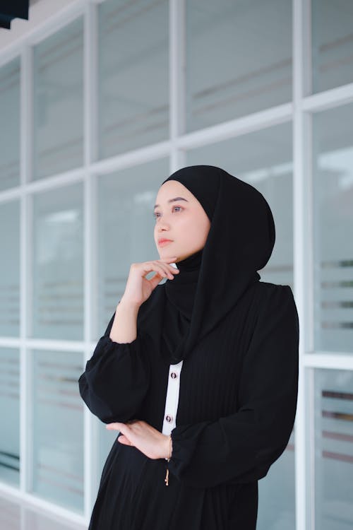 Woman in a Headscarf and a Blouse Standing with a Hand under her Chin