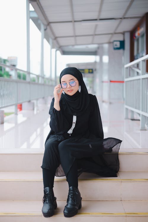 Woman in Eyeglasses and a Headscarf Sitting on the Steps