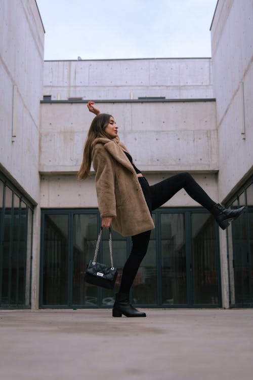 Fashionable Young Woman in a Dynamic Pose in front of a Building 