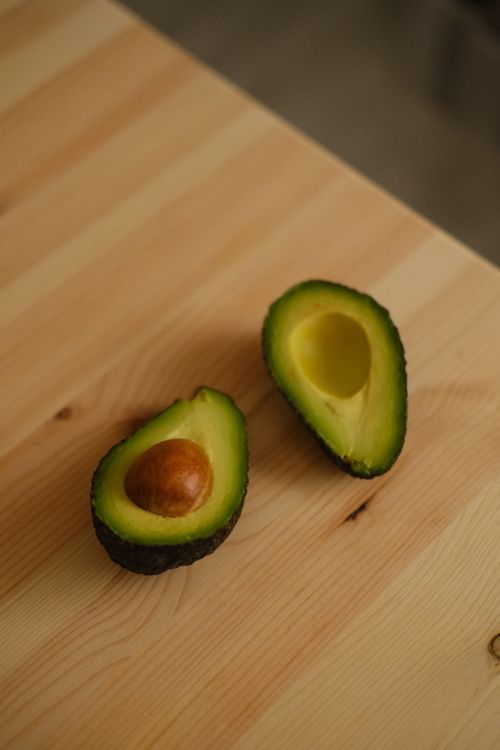 Free Close-up shot of ripe avocado halves on a wooden table, perfect for culinary uses. Stock Photo